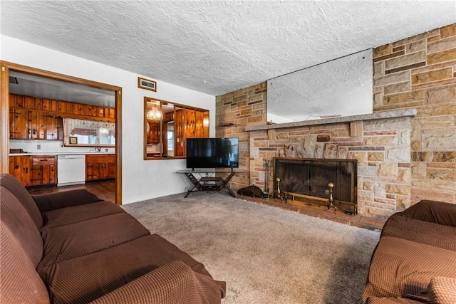 living area with visible vents, carpet flooring, a textured ceiling, and a stone fireplace