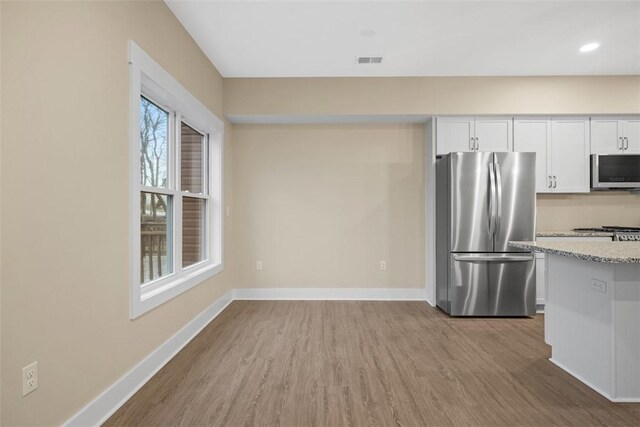1223 Center Ave, West View, PA 15229 - kitchen with wood finished floors, stainless steel appliances, white cabinets, baseboards, and light stone countertops