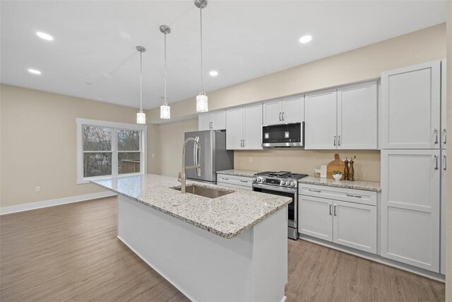 1223 Center Ave, West View, PA 15229 - kitchen with a center island with sink, wood finished floors, hanging light fixtures, stainless steel appliances, and a sink