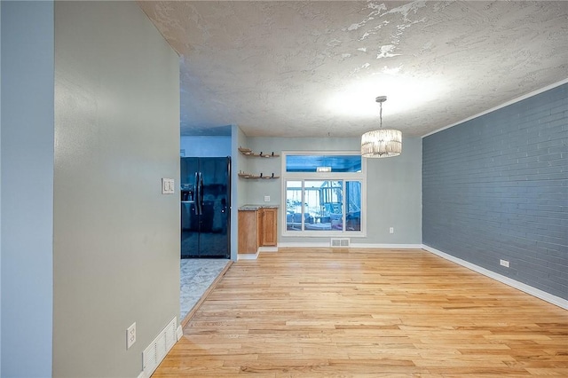 159 Mardi Gras Dr, Plum Boro, PA 15239 - unfurnished dining area with a notable chandelier, visible vents, brick wall, and light wood-style floors