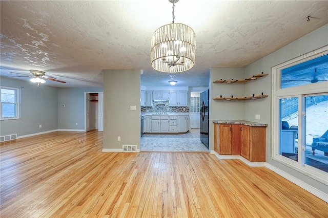 159 Mardi Gras Dr, Plum Boro, PA 15239 - kitchen featuring visible vents, backsplash, under cabinet range hood, light wood-style flooring, and freestanding refrigerator