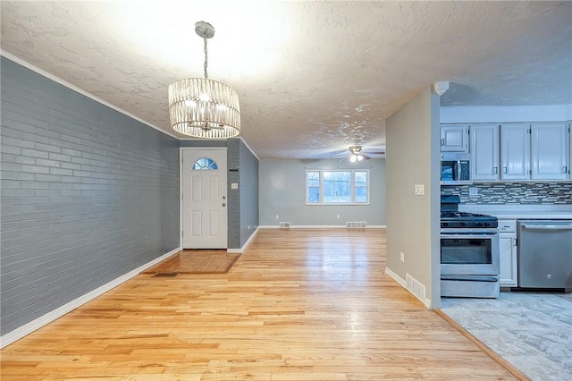 159 Mardi Gras Dr, Plum Boro, PA 15239 - entrance foyer with visible vents, light wood-style floors, brick wall, and a textured ceiling