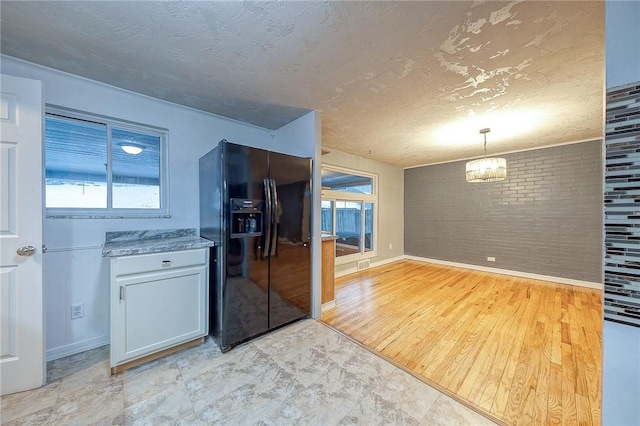 159 Mardi Gras Dr, Plum Boro, PA 15239 - kitchen with a textured ceiling, brick wall, a chandelier, and black refrigerator with ice dispenser