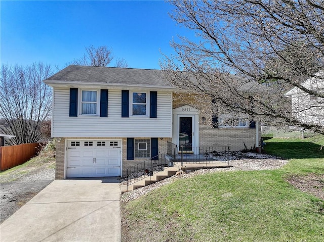 split foyer home featuring concrete driveway, an attached garage, brick siding, and a front lawn