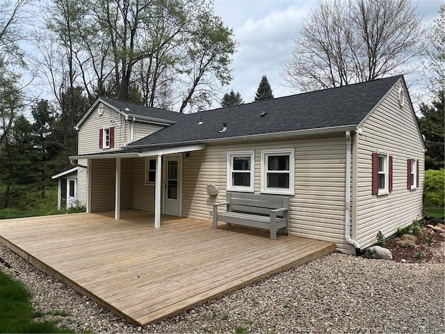 back of house with roof with shingles and a deck