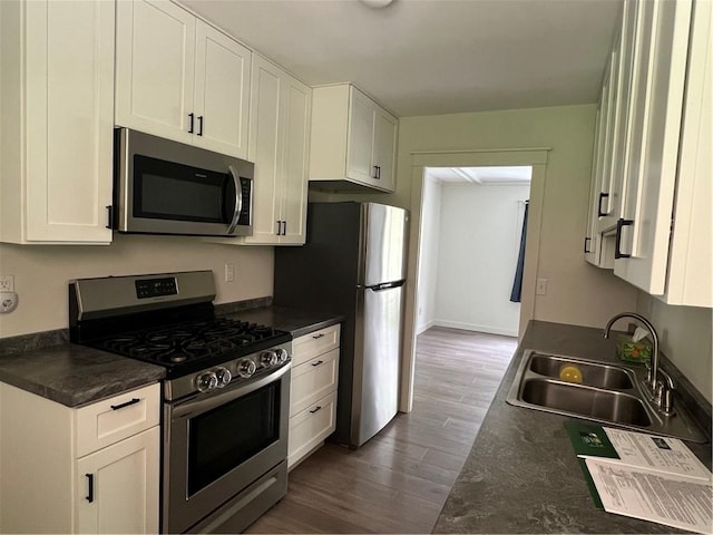 kitchen with a sink, appliances with stainless steel finishes, white cabinets, and dark wood-style floors