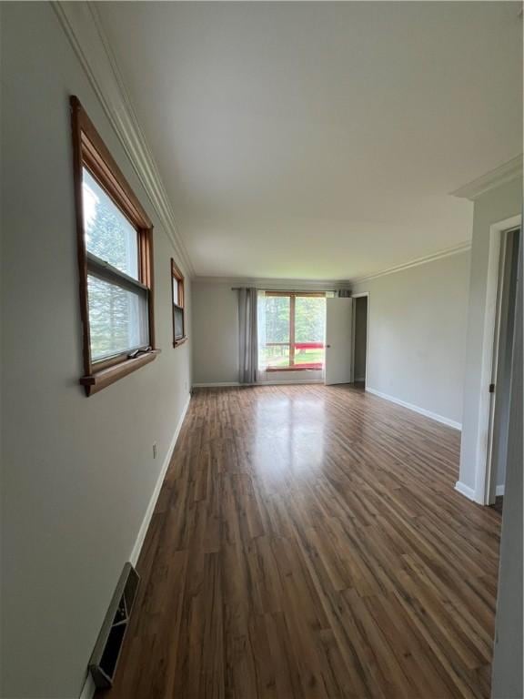 spare room featuring crown molding, baseboards, visible vents, and wood finished floors
