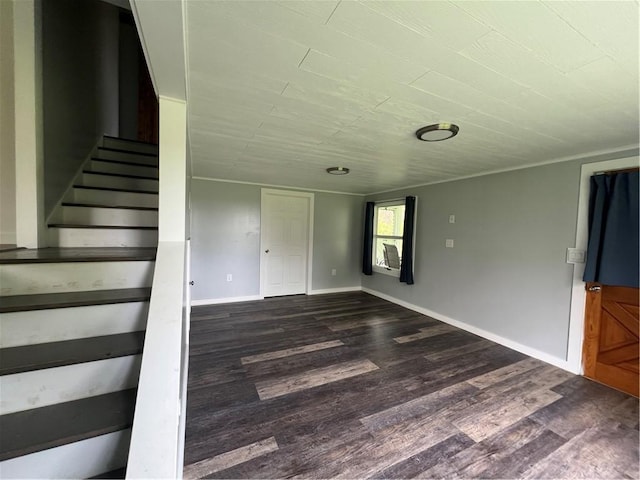 unfurnished living room featuring stairs, baseboards, and dark wood-type flooring