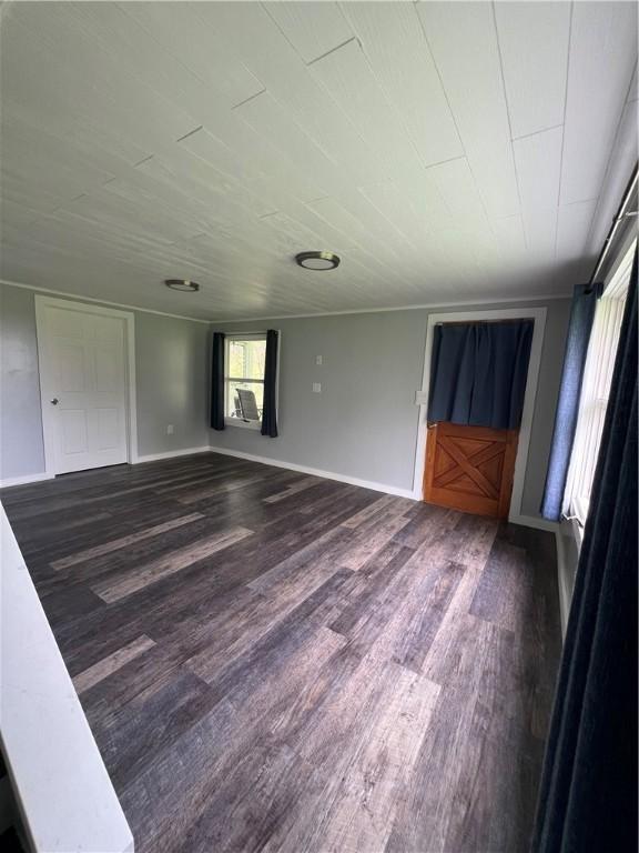 unfurnished room featuring baseboards, dark wood finished floors, and wood ceiling