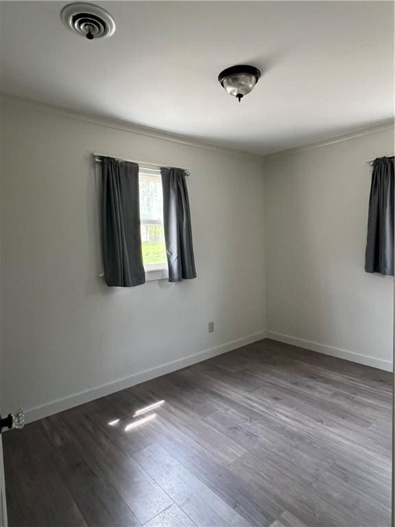 spare room featuring baseboards, wood finished floors, and visible vents