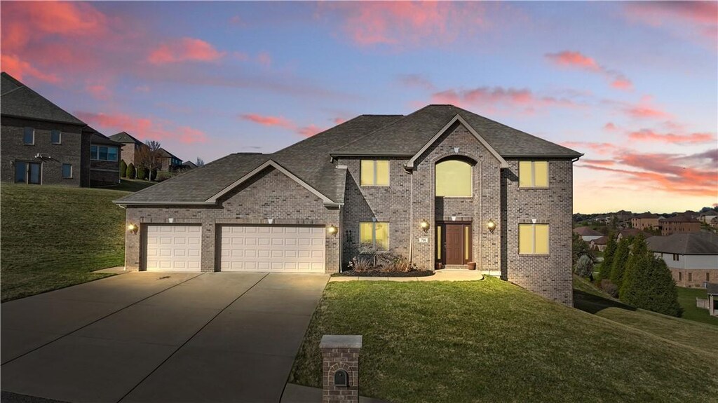 view of front of home featuring brick siding, a front yard, driveway, and an attached garage