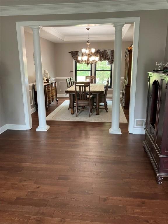 123 Windermere Ct, Peters Twp, PA 15317 - dining area featuring dark wood-style flooring, a chandelier, crown molding, ornate columns, and a decorative wall