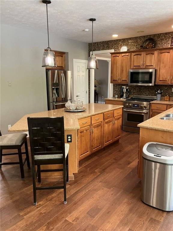 123 Windermere Ct, Peters Twp, PA 15317 - kitchen with appliances with stainless steel finishes, dark wood-style flooring, a kitchen island, tasteful backsplash, and a textured ceiling