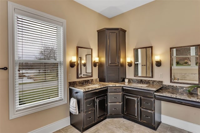 full bathroom with double vanity, a sink, and baseboards