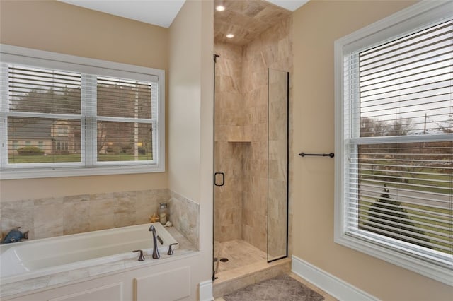 full bath featuring a stall shower, baseboards, and a garden tub