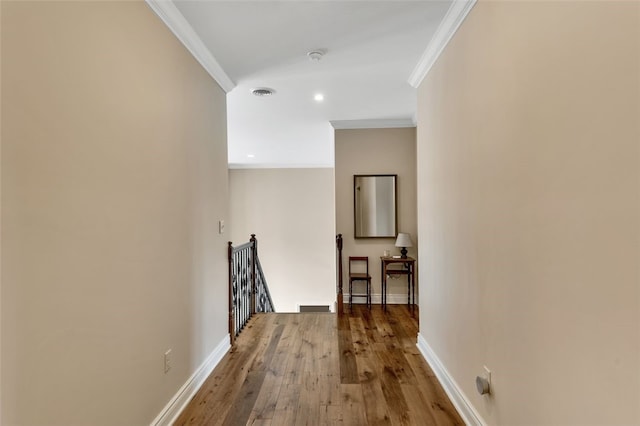 hallway with baseboards, visible vents, and crown molding