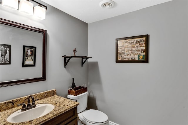 bathroom with toilet, vanity, and visible vents