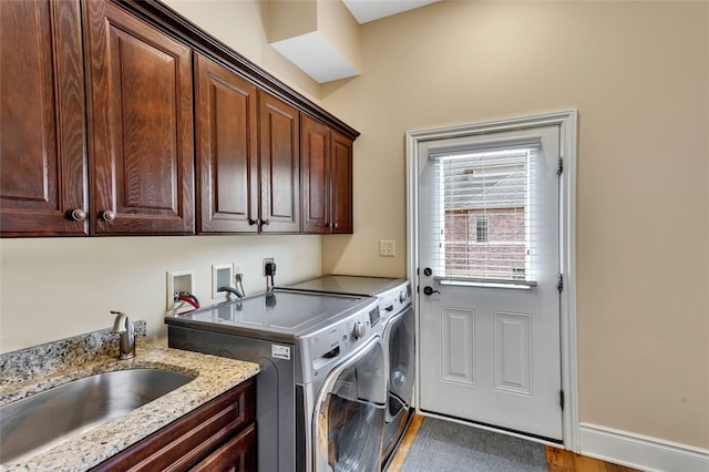 laundry room featuring independent washer and dryer, cabinet space, a sink, and baseboards