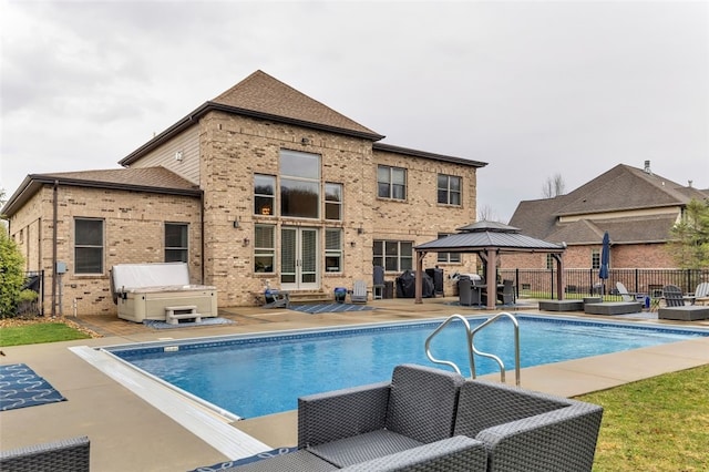 view of pool with a hot tub, fence, a gazebo, and a patio area