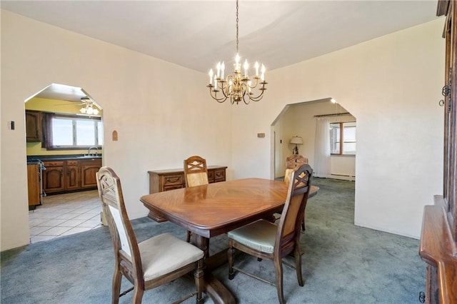 dining area with a chandelier, arched walkways, a healthy amount of sunlight, and light colored carpet