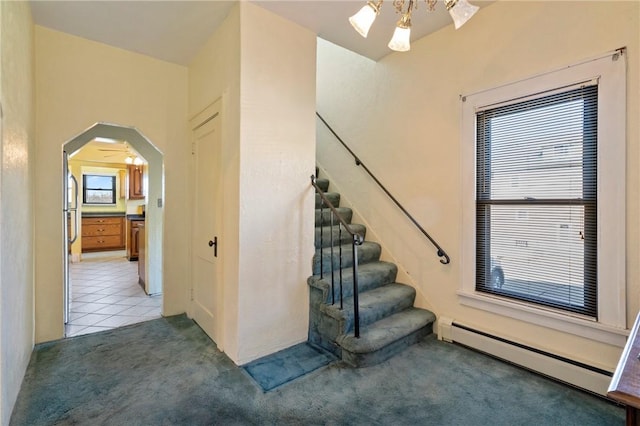staircase featuring tile patterned floors, arched walkways, carpet floors, and a baseboard radiator