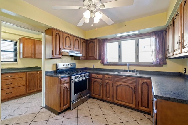 kitchen featuring dark countertops, a sink, stainless steel gas range oven, and under cabinet range hood
