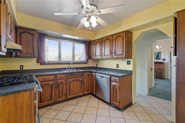 kitchen featuring stainless steel appliances, under cabinet range hood, dark countertops, ceiling fan, and a sink