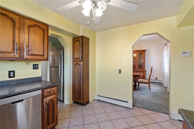 kitchen featuring appliances with stainless steel finishes, dark countertops, ceiling fan, a baseboard heating unit, and arched walkways