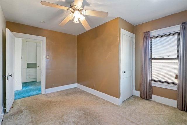 unfurnished bedroom with light colored carpet, a ceiling fan, and baseboards