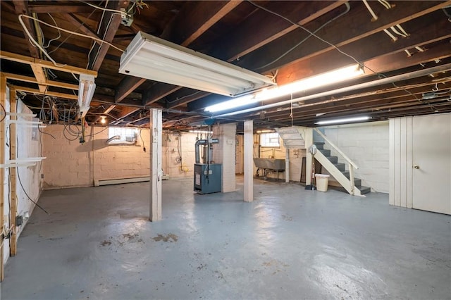basement featuring heating unit, stairs, and a sink