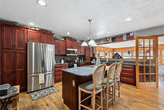 19 Misty Meadows Ln, Menallen Twp, PA 15401 - kitchen featuring stainless steel appliances, dark brown cabinets, light wood-style flooring, a textured ceiling, and an island with sink