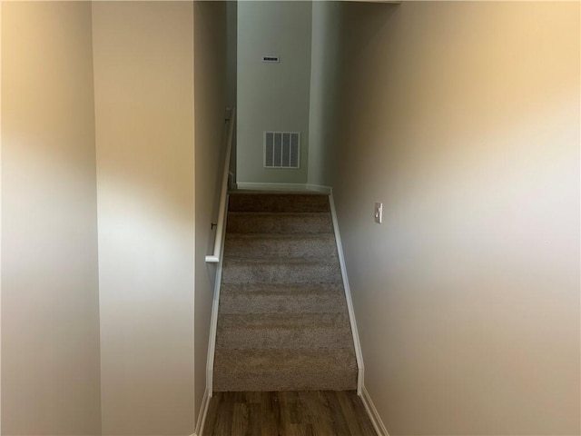 stairs featuring visible vents, baseboards, and wood finished floors
