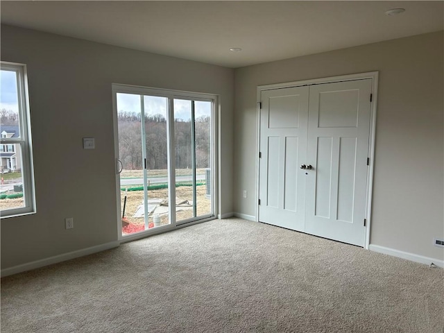 unfurnished bedroom featuring a closet, baseboards, access to outside, and carpet