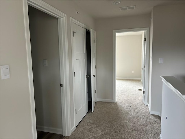 hallway featuring baseboards, carpet, and visible vents