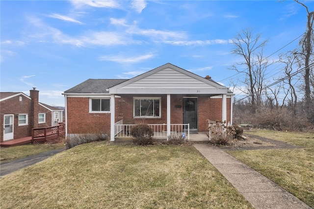 bungalow-style house with brick siding, covered porch, and a front yard
