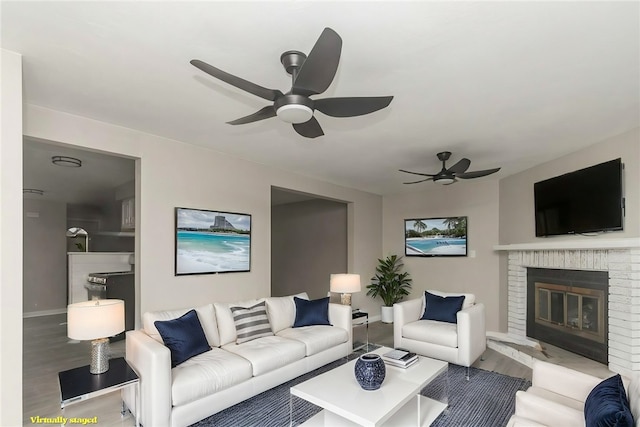 living room with wood finished floors, baseboards, a fireplace, and ceiling fan