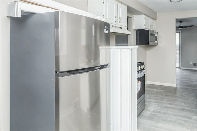 kitchen featuring white cabinetry, under cabinet range hood, baseboards, light wood-style floors, and appliances with stainless steel finishes