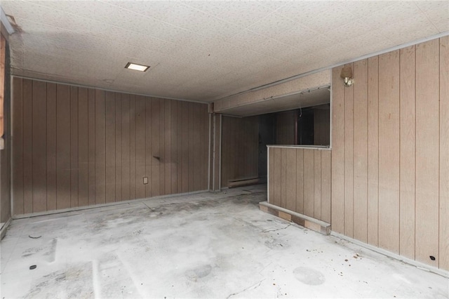 empty room featuring unfinished concrete floors and wooden walls