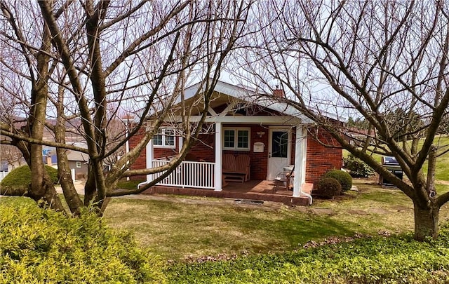 view of front of property with a chimney, a front yard, and brick siding