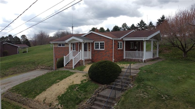 view of front facade with covered porch, a front lawn, brick siding, a chimney, and driveway