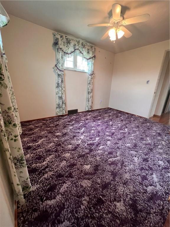 empty room with carpet flooring and a ceiling fan