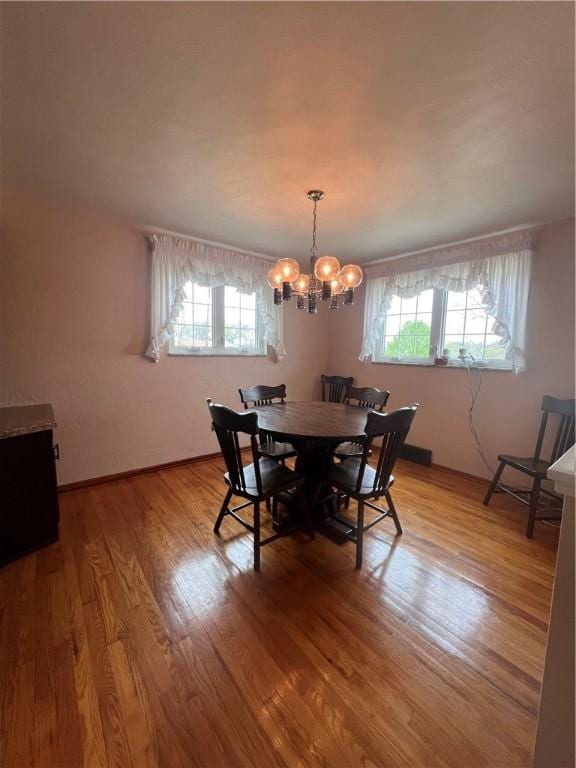 dining area with light wood-type flooring, an inviting chandelier, and a healthy amount of sunlight