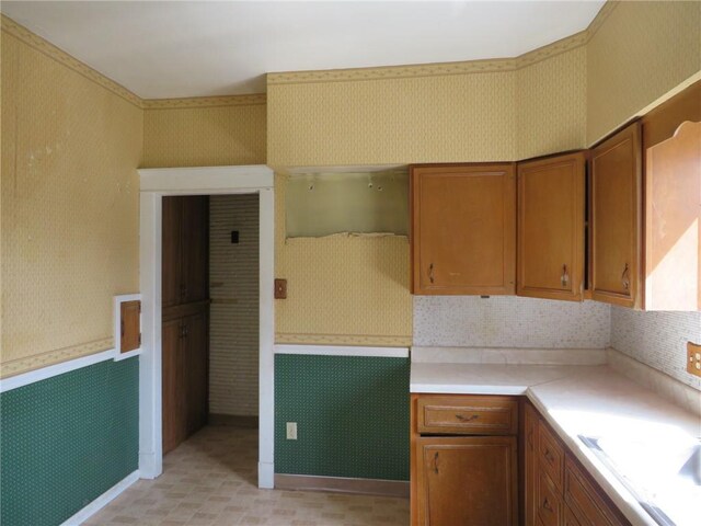 437 Shady Ave, Charleroi Boro, PA 15022 - kitchen with wallpapered walls, brown cabinetry, and light countertops