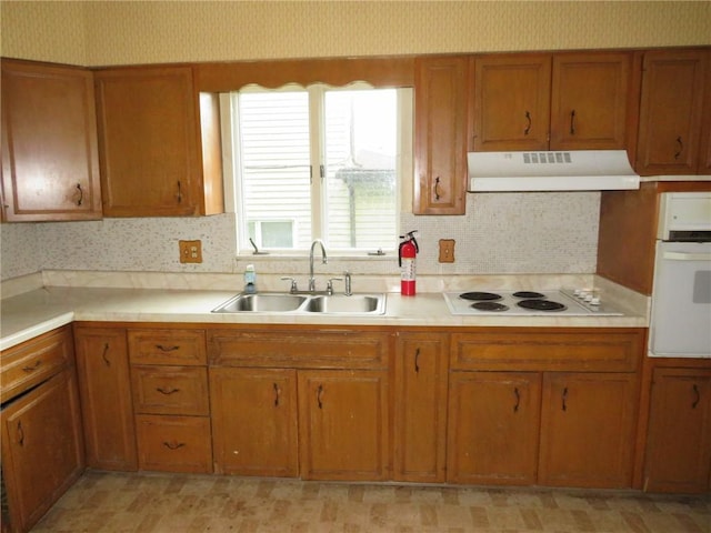 437 Shady Ave, Charleroi Boro, PA 15022 - kitchen with under cabinet range hood, white appliances, brown cabinetry, wallpapered walls, and light countertops