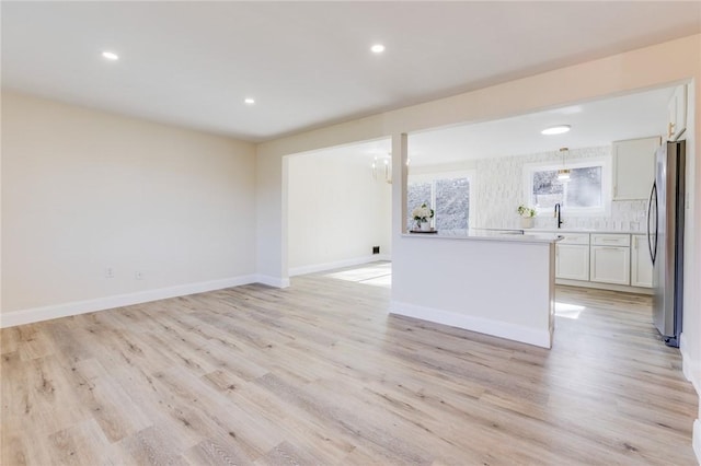 130 Castle, West Mifflin, PA 15122 - unfurnished living room featuring light wood finished floors, baseboards, recessed lighting, a sink, and a notable chandelier