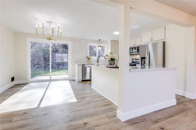 130 Castle, West Mifflin, PA 15122 - kitchen with light wood-style flooring, stainless steel appliances, white cabinetry, a sink, and an inviting chandelier