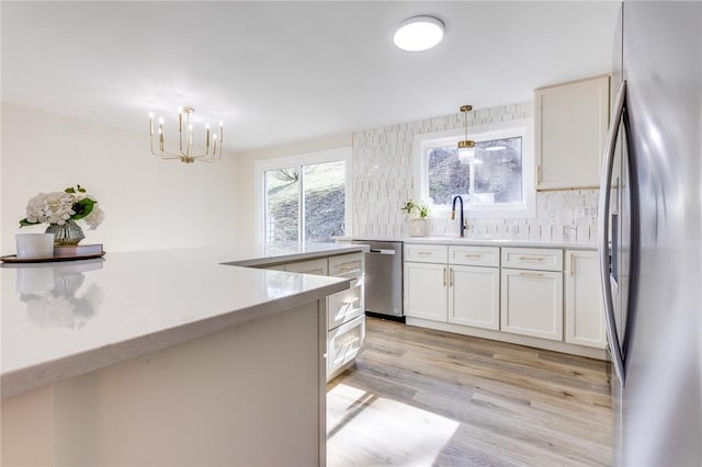 130 Castle, West Mifflin, PA 15122 - kitchen featuring a sink, light wood finished floors, appliances with stainless steel finishes, decorative light fixtures, and an inviting chandelier