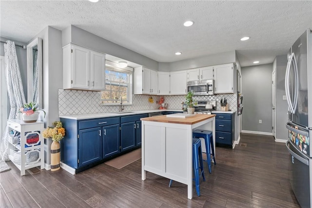 145 Brighton Ln, Adams Twp, PA 16046 - kitchen featuring stainless steel appliances, blue cabinetry, butcher block countertops, white cabinets, and a textured ceiling