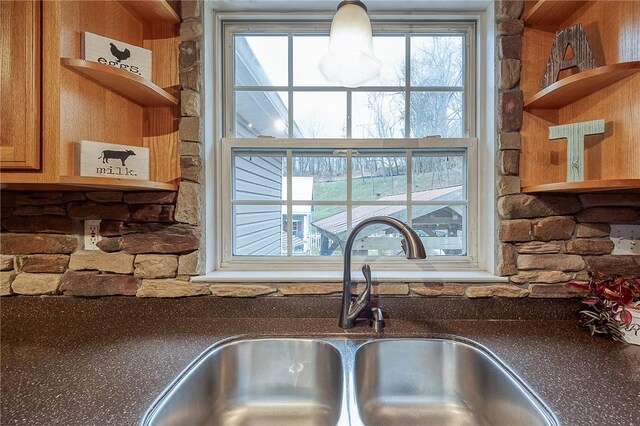 kitchen view of open shelves, a sink, and brown cabinets