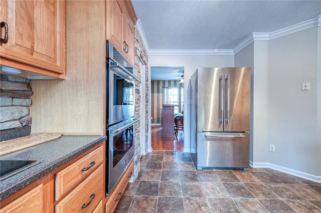 kitchen with stainless steel appliances, baseboards, dark stone finish flooring, ornamental molding, and a textured ceiling